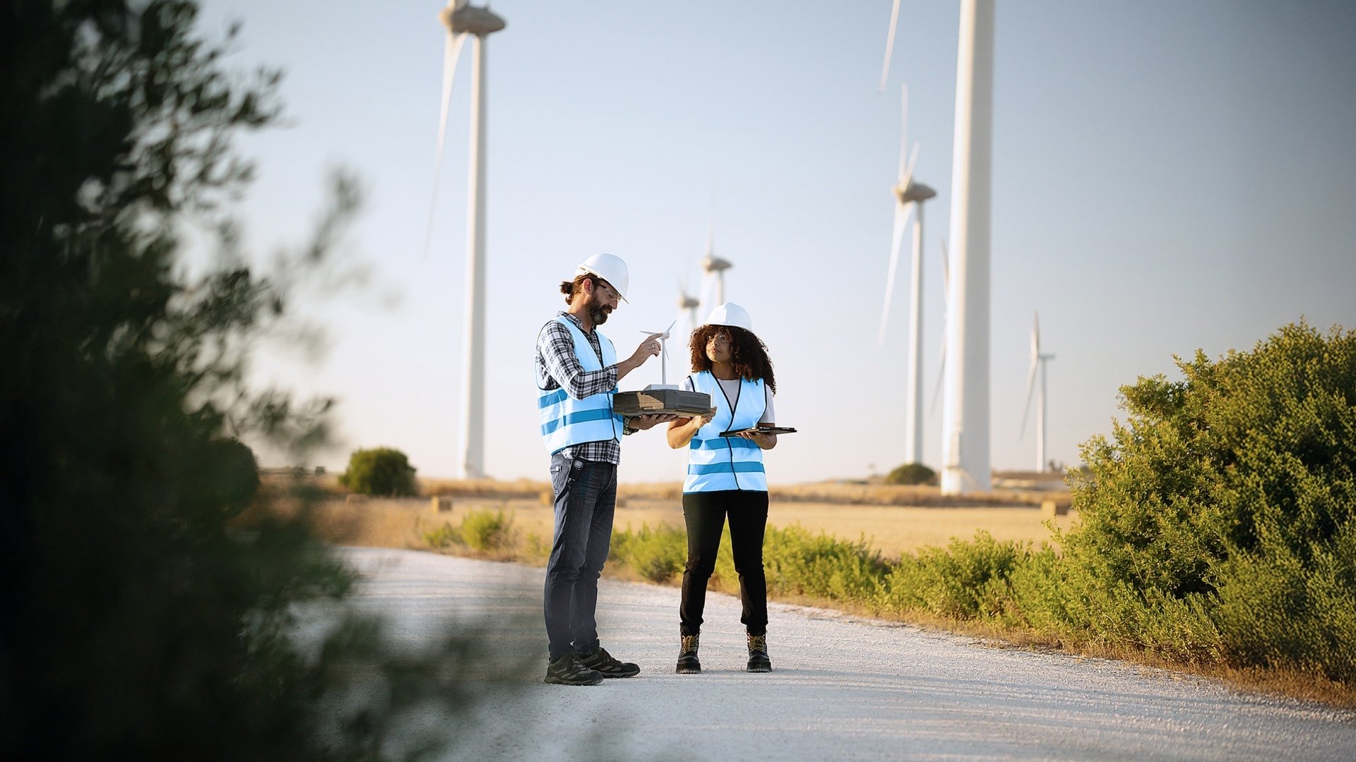 Zwei Field Service Mitarbeitende vor Windrädern bei der Wissensübergabe